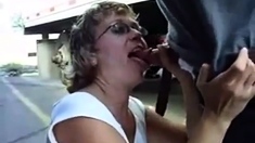 Mature woman sucks cock between trucks in parking lot